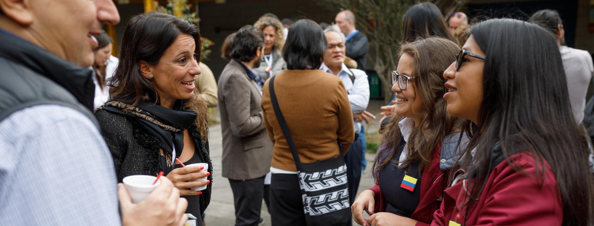 Three women and a man of diverse ethnicities smile as they speak to each other