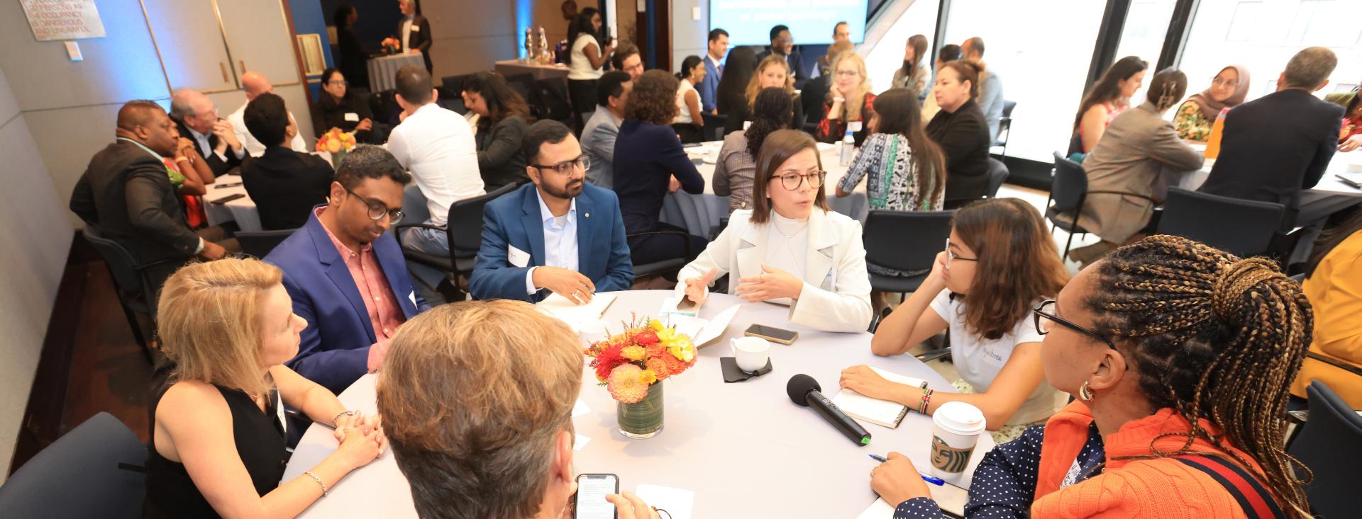 A group of diverse adults sit around a table in discussion 