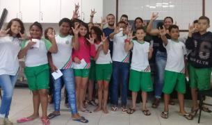 A group of students pose demonstrating the Libras sign for "I love you"