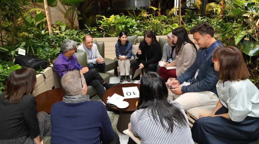 A diverse group of adults sit around a table in conversation