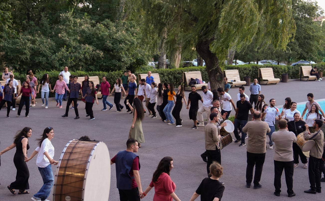 A large group of people dance outdoors