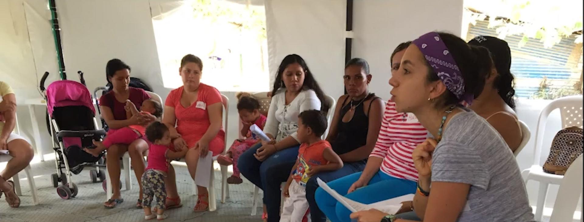 A young woman meets with a group of mothers and teenage daughters