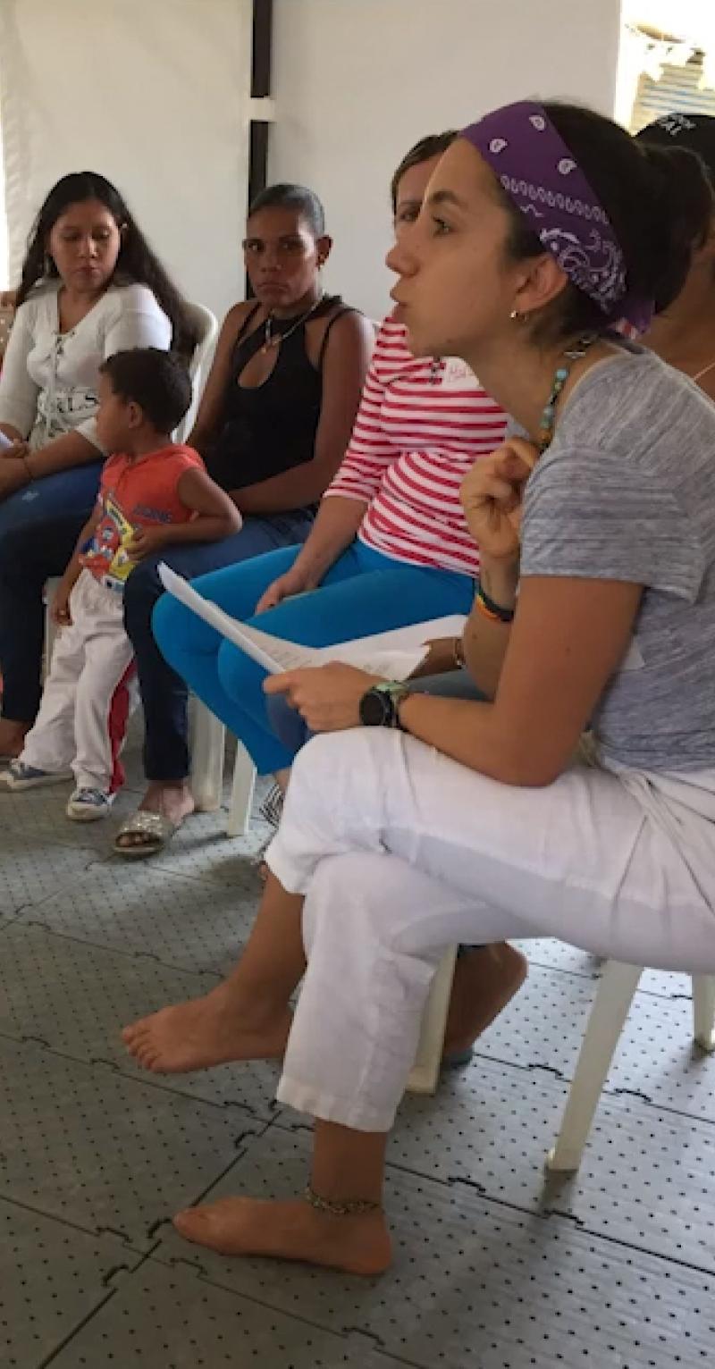A young woman meets with a group of mothers and teenage daughters