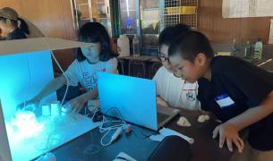 Three Asian children experiment with a light box and computer